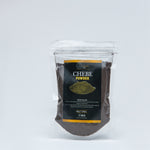 A clear resealable bag of Chebe Powder, with a black and gold label. The label shows the product name 